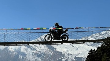 Moto sur une passerelle devant l'Himalaya