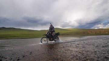 Moto qui traverse un gué dans la steppe